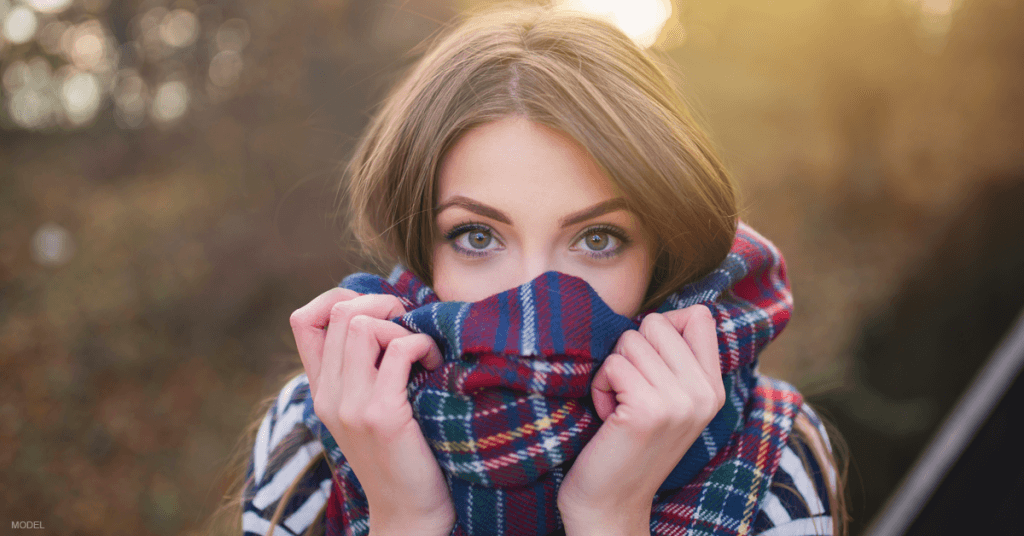 A woman covers her face with a scarf.