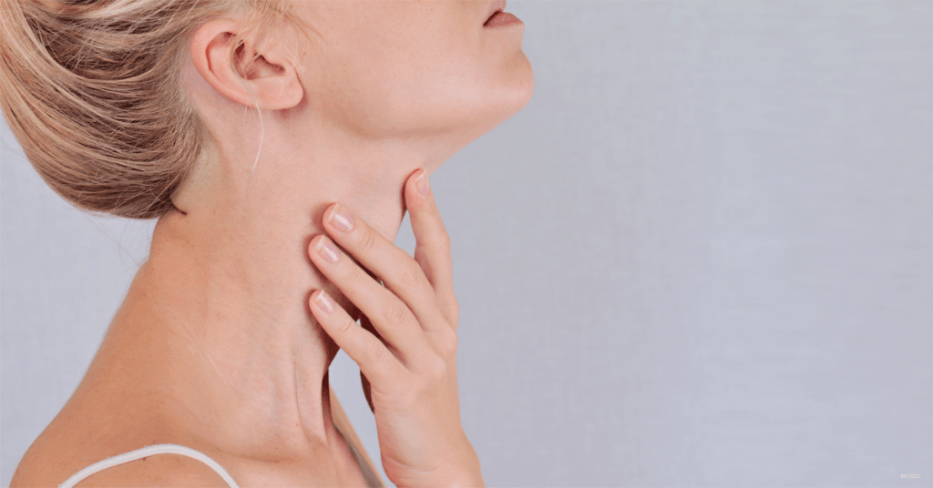 Blonde woman holding her neck.