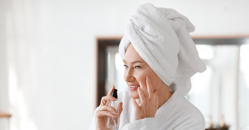 A woman looks happy in the mirror after getting injectable treatment.