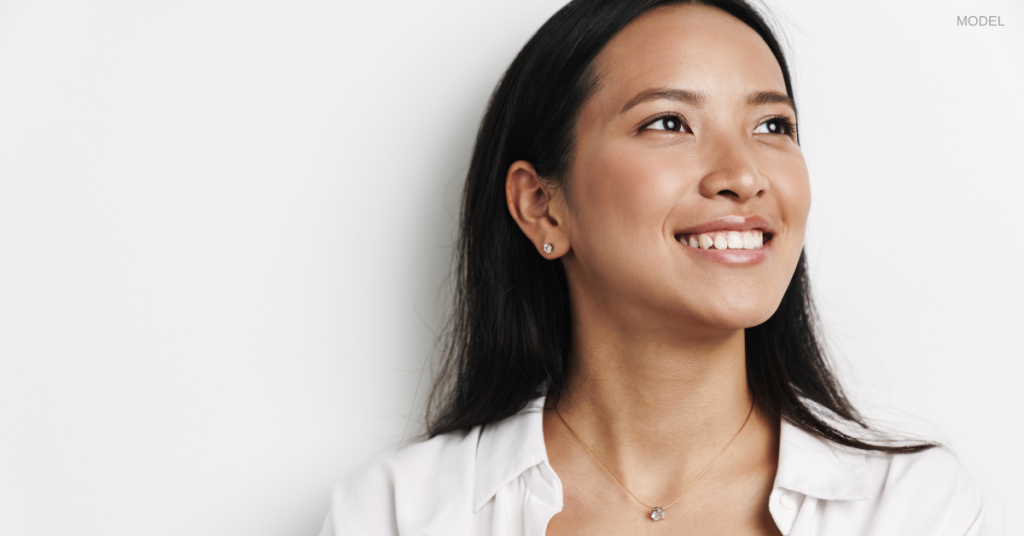 Woman in a white shirt smiling while looking away from the camera (model)