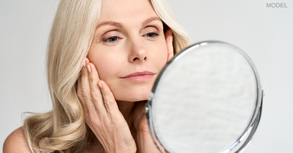 Older woman looking at her reflection in the mirror (model)