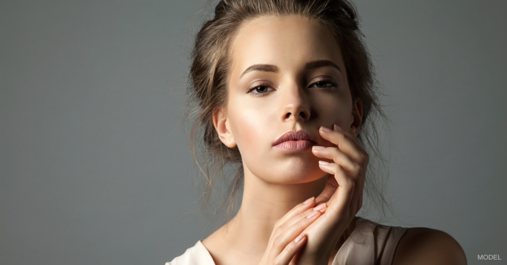 Woman (model) holds a hand up to her face.